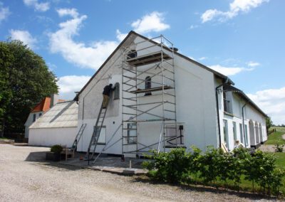 Man on scaffolds painting a house during exterior renovations